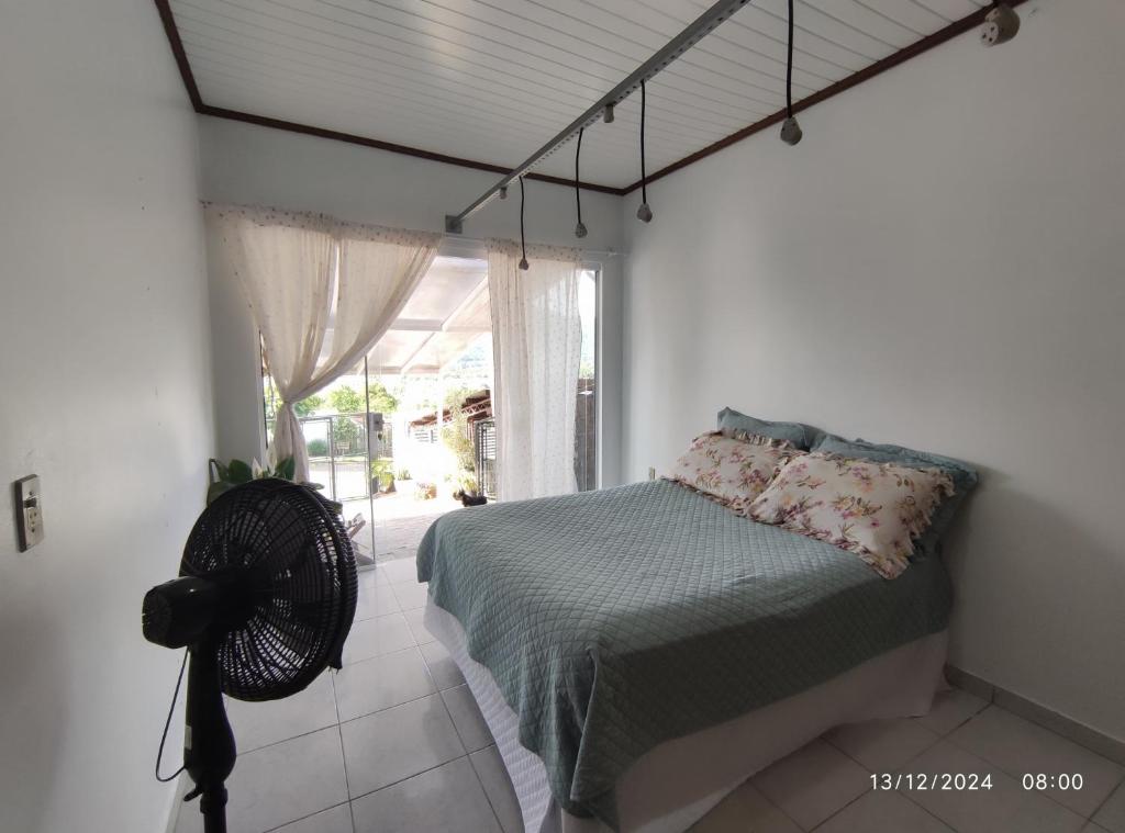 a bedroom with a bed with a fan and a window at Quartos familiares com piscina in Encantado