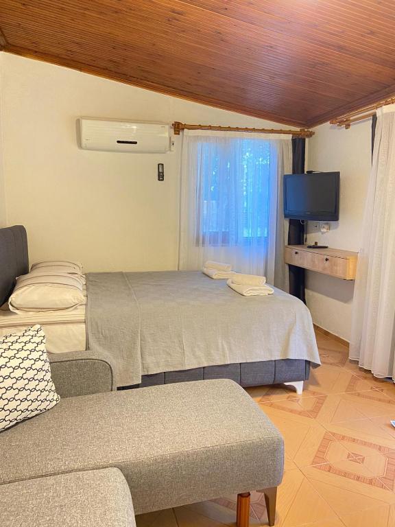 a room with a bed and a couch and a tv at Arya nature çiftlik in Marmaris