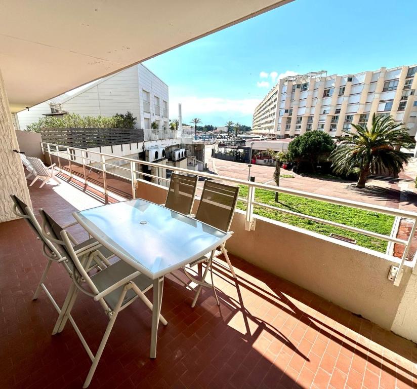 une table et des chaises sur un balcon avec vue sur une ville dans l'établissement ST CYPRIEN PORT APPARTEMENT T3 TERRASSE -PARKING 50 M des PLAGES, à Saint Cyprien Plage
