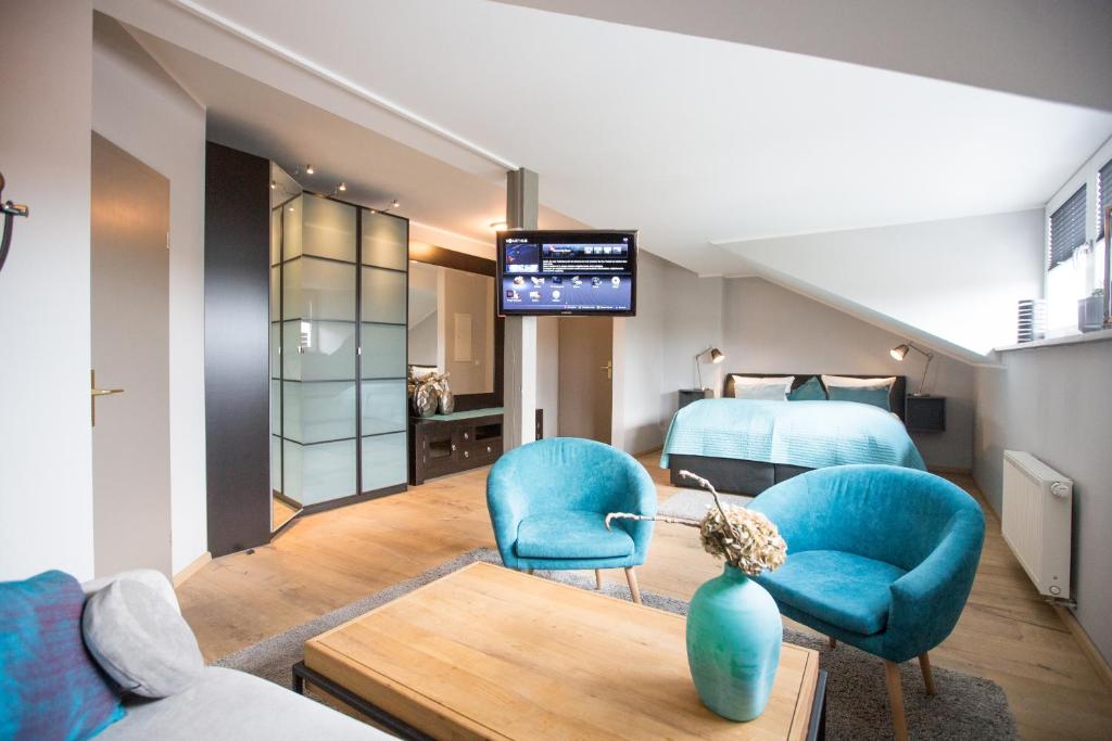 Zimmer mit zwei blauen Stühlen und einem Schlafzimmer in der Unterkunft Hotel & Restaurant Fackelgarten Plau am See in Plau am See