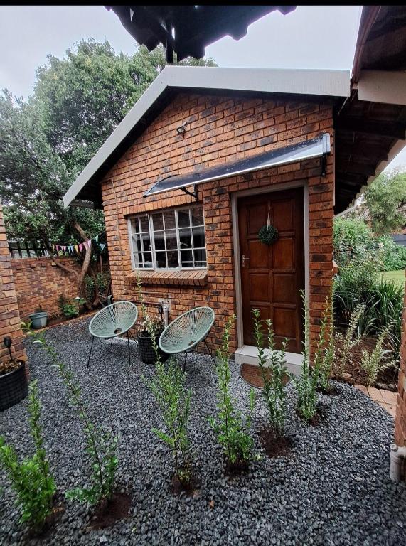 ein Backsteingebäude mit zwei Stühlen davor in der Unterkunft Sweetpea in Boksburg