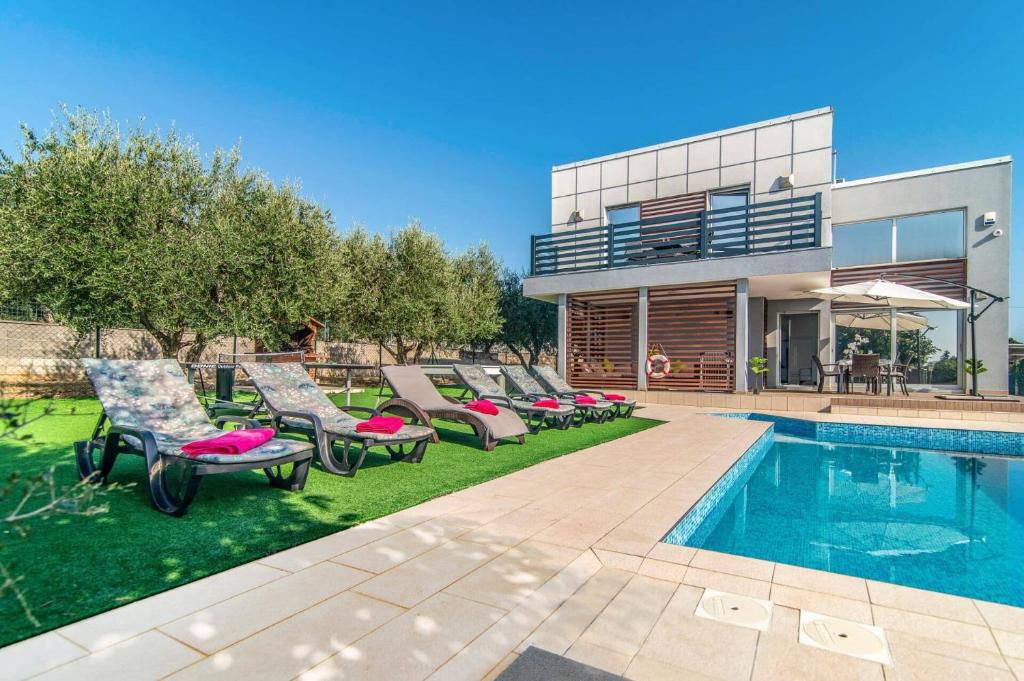 a house with a swimming pool and chairs next to a house at Villa Tammy by Villa Plus in Vodnjan