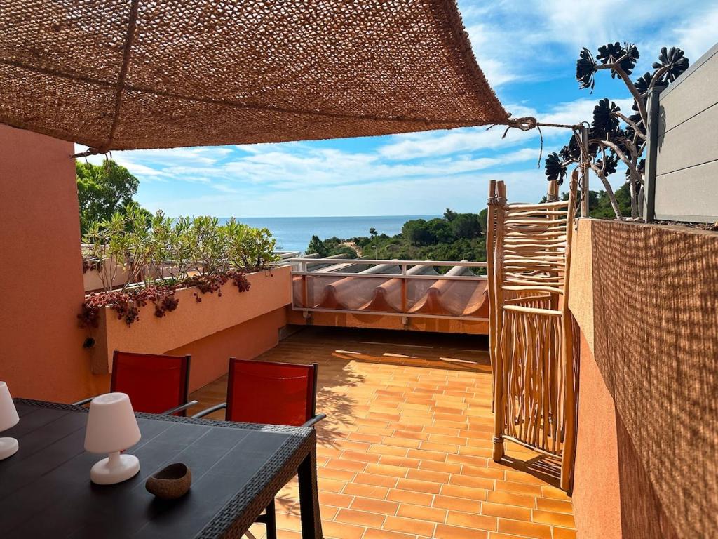 un patio avec une table et des chaises et une vue sur l'océan dans l'établissement Le 70, vue mer, climatisé, à deux pas de la plage, à Cavalaire-sur-Mer