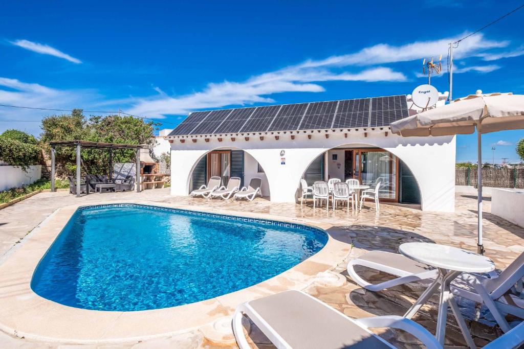 a villa with a swimming pool and a house at Villa Chiquita in Cala'n Porter