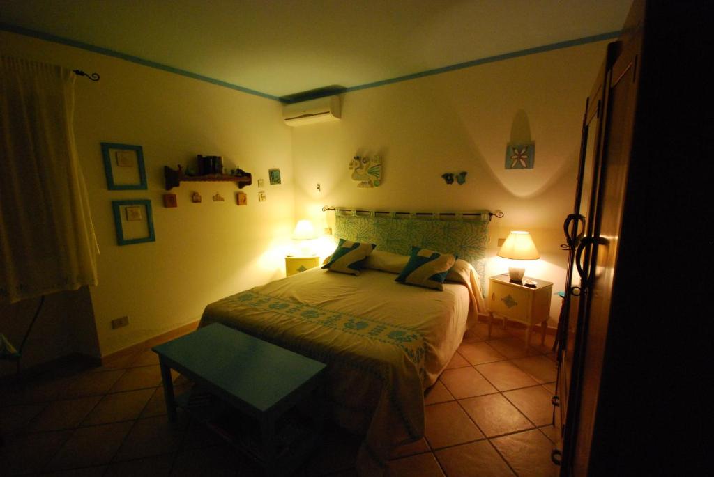 1 dormitorio con 1 cama con 2 lámparas y 1 mesa en Narboni Mannu, en Teulada