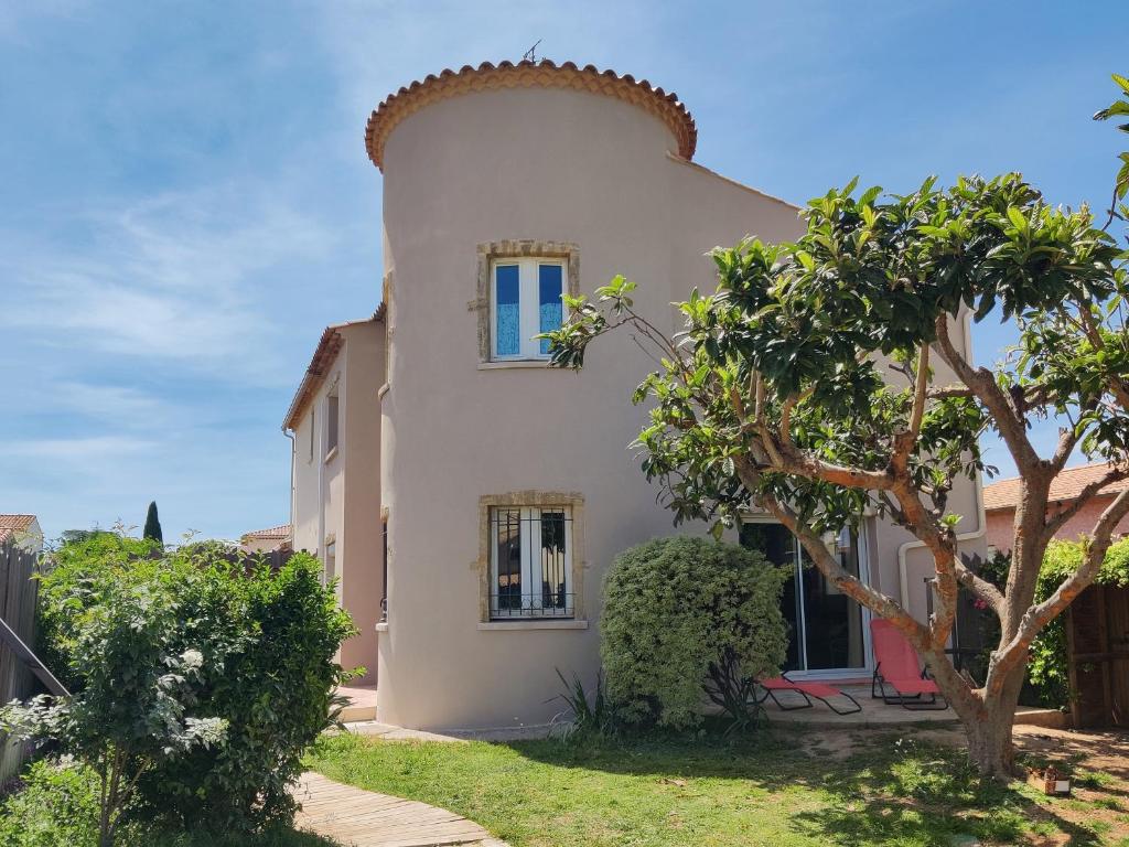 une grande maison blanche avec un arbre devant dans l'établissement Villa Douceur de Vivre à 15 min de la plage, à Villeneuve-lès-Maguelone