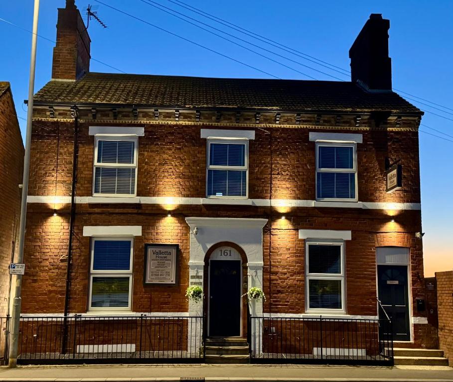 an old brick house on a street at Valletta House Holiday Apartments in Skegness