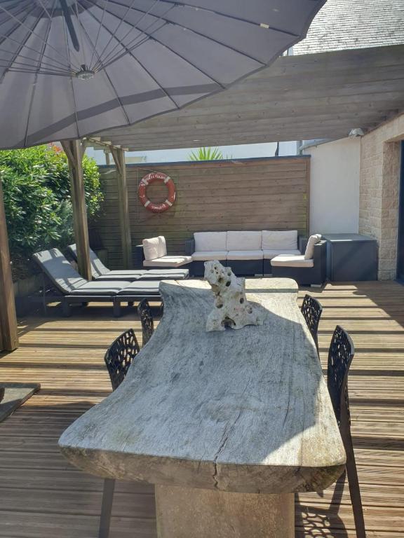 une table avec des chaises et un parasol sur une terrasse dans l'établissement Maison Les Aygals 300 m de la plage, 3 suites parentales, à Saint-Pierre-Quiberon
