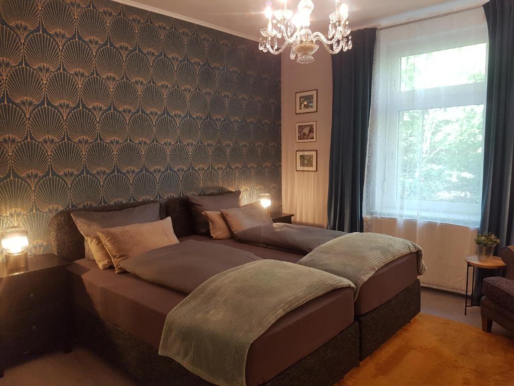 a bedroom with a large bed and a chandelier at Einführungspreis Gemütliche Auszeit - Designwohnung - 4 Sterne Hotelboxspringbetten - Küche - Familie - Erdgeschoss in Recklinghausen