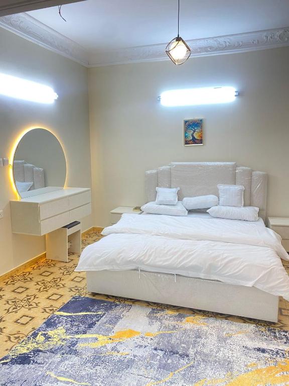 a bedroom with a large white bed and a mirror at نزل القمريه in Taif