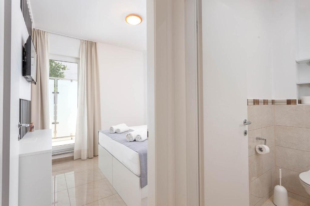 a white bathroom with a sink and a window at Sunset Split Rooms in Podstrana