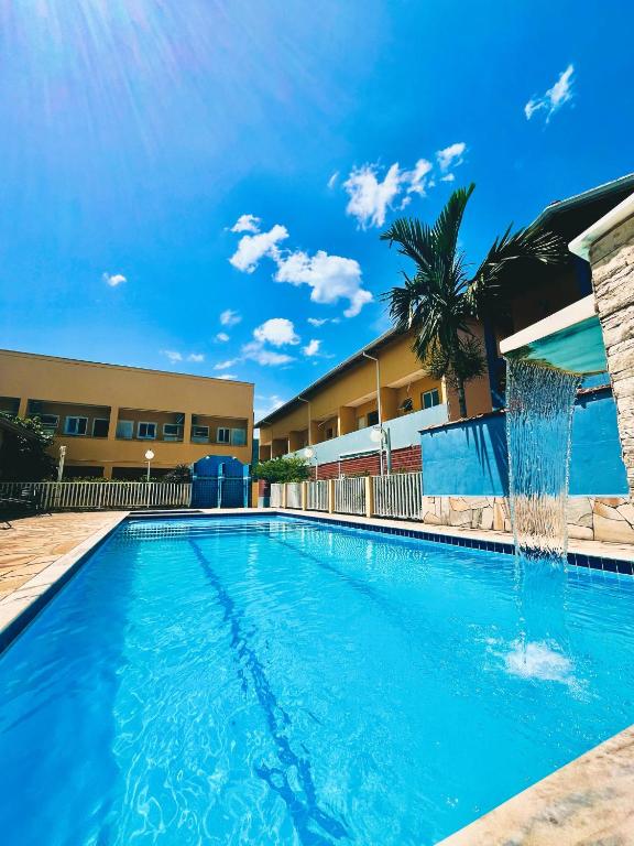 a swimming pool with a fountain in front of a building at Pousada Caraguá in Caraguatatuba