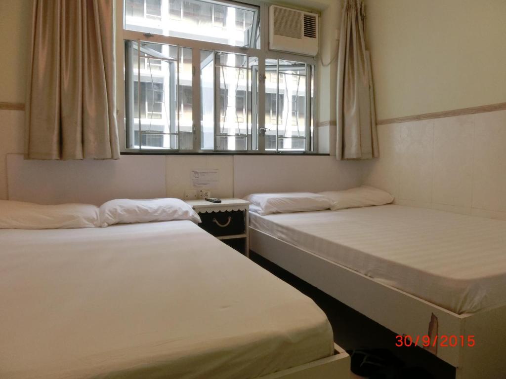 two beds in a room with a window at Li Cheng Guesthouse in Hong Kong