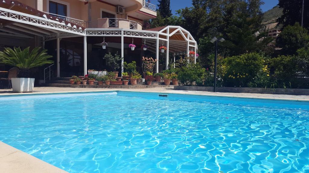 a swimming pool in front of a house at JB Hotel in Sarandë