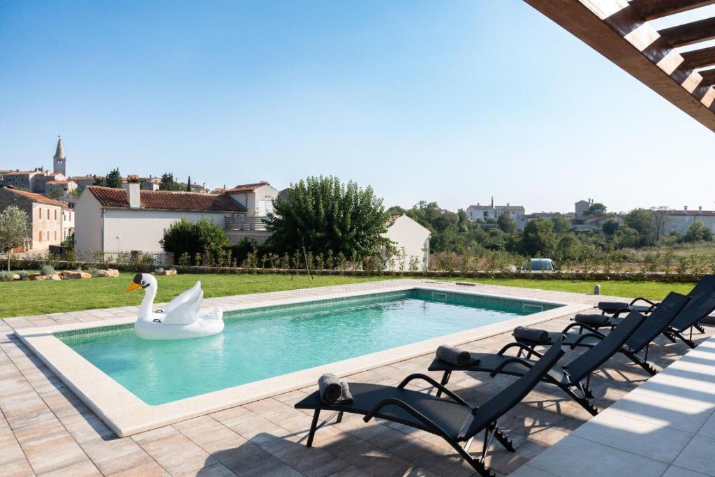 un cigno che nuota in una piscina con sedie di Villa Veduta a Bale (Valle)