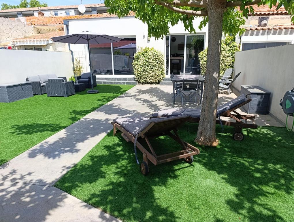 une cour arrière avec une table, un arbre et un patio dans l'établissement Maison vias village, à La Celle-sous-Gouzon