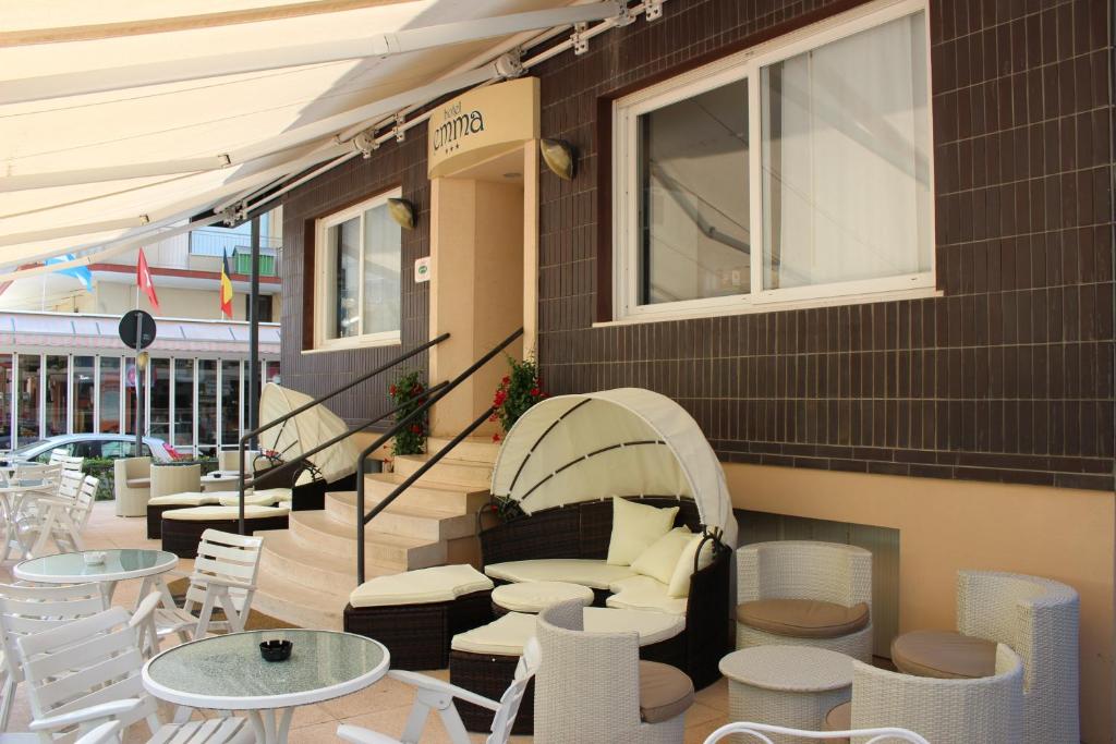 un patio avec des chaises et des tables blanches et un bâtiment dans l'établissement Hotel Emma, à Cattolica