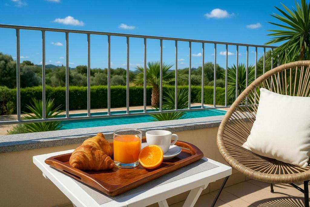 a tray of orange juice and croissants on a table on a balcony at Green Villetta with a pool in Viddalba