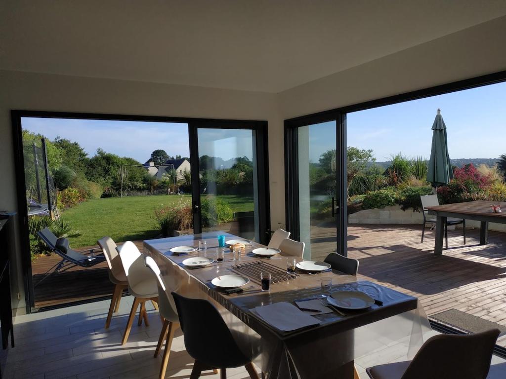 - une salle à manger avec une table, des chaises et de grandes fenêtres dans l'établissement Belle maison entre mer et campagne, à Plouzané
