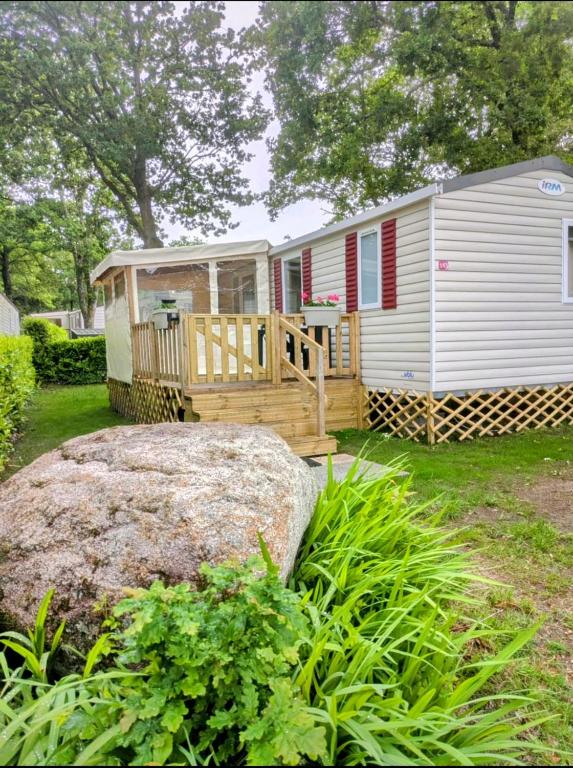 un mobil-home avec un porche et un gros rocher dans l'établissement mobil home Eleganzia domaine de kerlann, à Pont-Aven