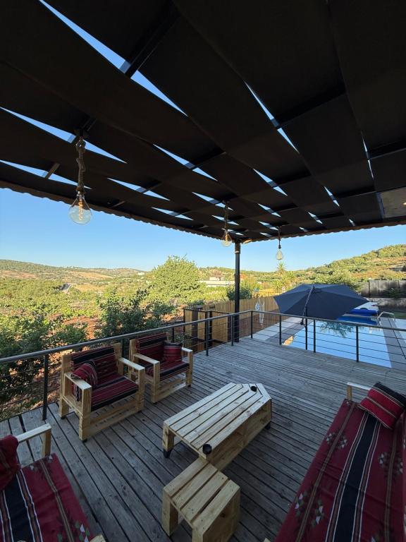 a wooden deck with benches and an umbrella at Oak Farm مزرعة البلوط in Ajloun