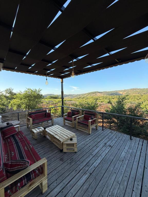 a deck with benches and chairs on a roof at Oak Farm مزرعة البلوط in Ajloun