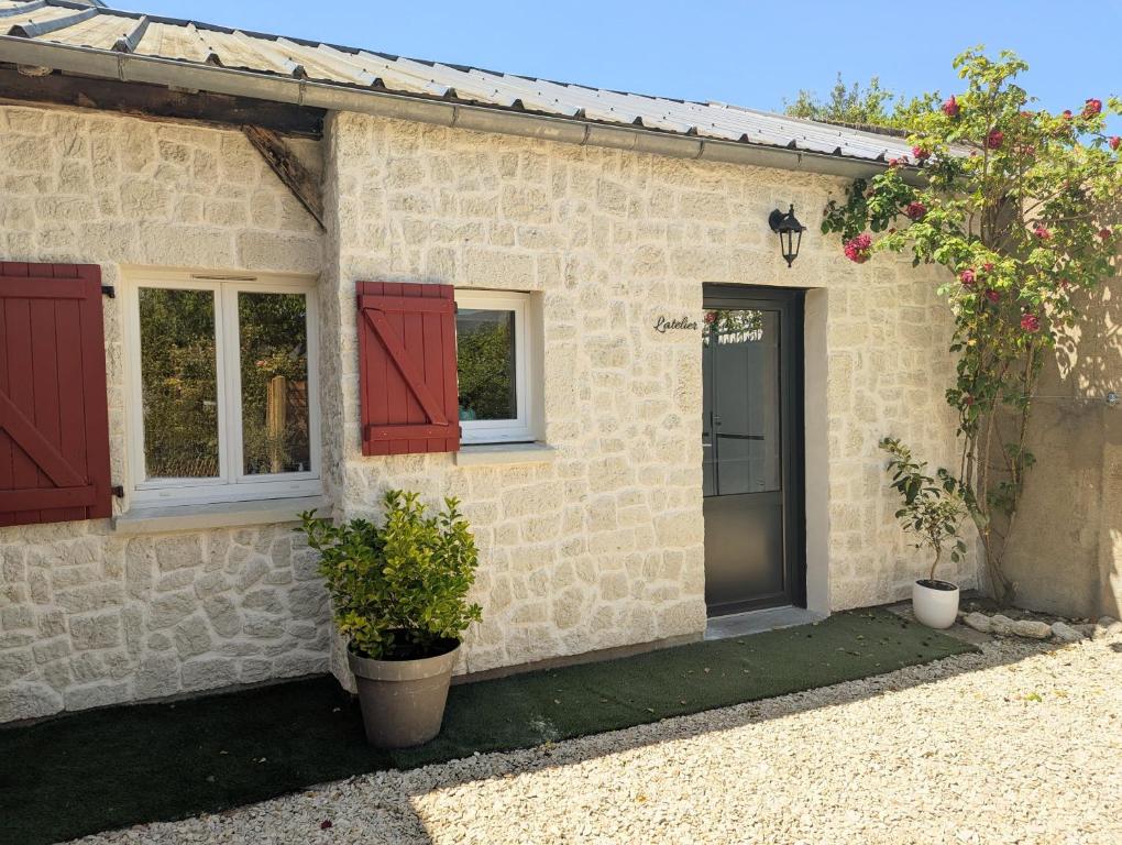 a small stone house with red doors and windows at L'atelier au coeur de Meung in Meung-sur-Loire