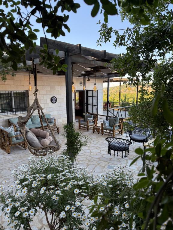 a patio with a hammock and benches in a yard at Oak Farm مزرعة البلوط in Ajloun