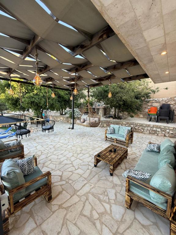 a patio with couches and benches on a stone floor at Oak Farm مزرعة البلوط in Ajloun