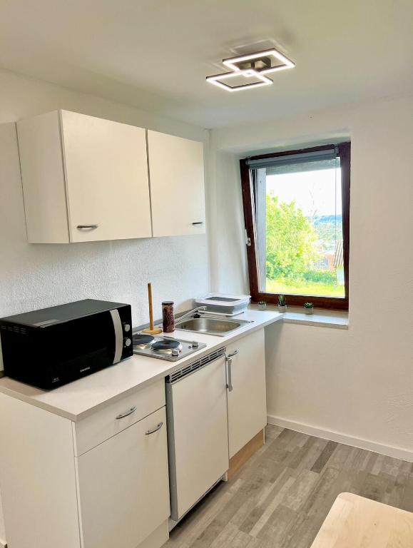a kitchen with white cabinets and a microwave at Apartment mit Gartenblick in Spiesen-Elversberg