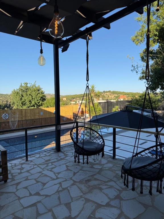 two swings on a patio with a view at Oak Farm مزرعة البلوط in Ajloun