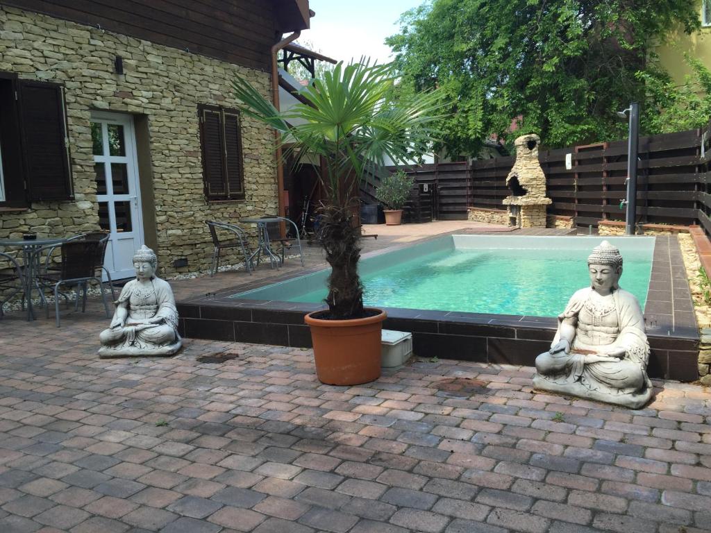 tres estatuas de monjes sentados junto a una piscina en Smeraldo Villa, en Siófok