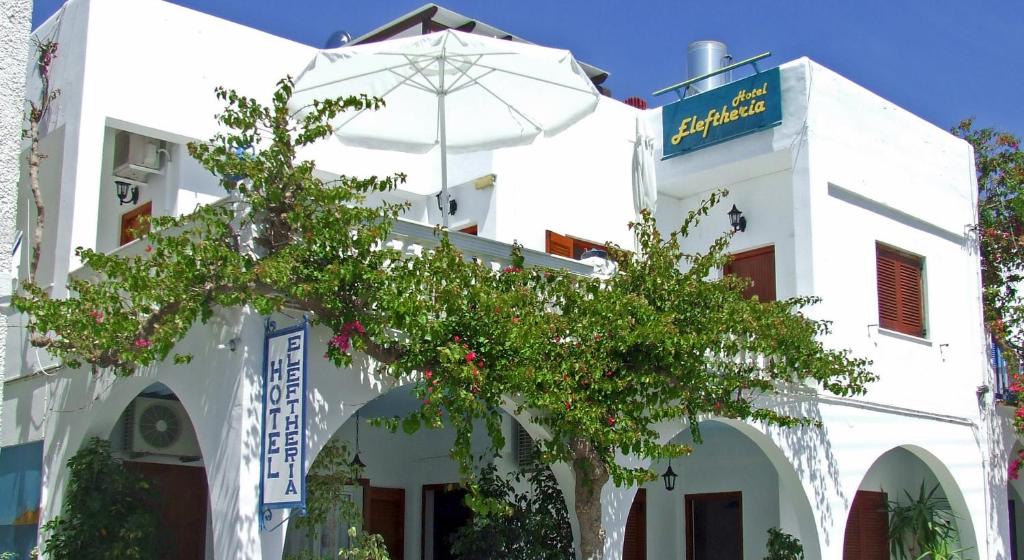 ein weißes Gebäude mit einem Baum davor in der Unterkunft Hotel Eleftheria in Parikia
