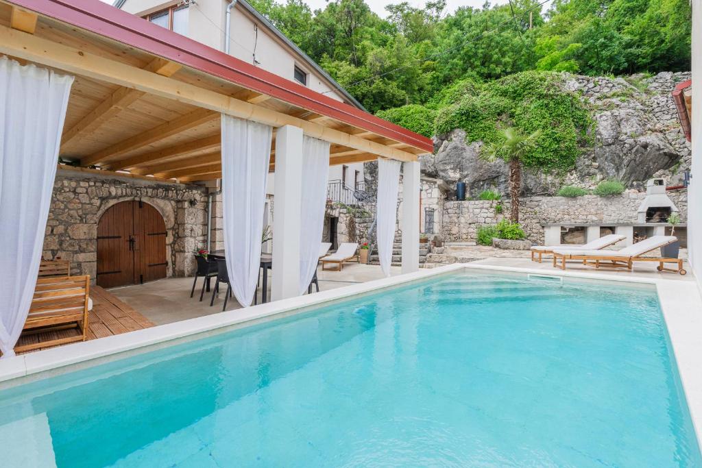 a swimming pool with a patio and a house at Villa Marisan in Bribir