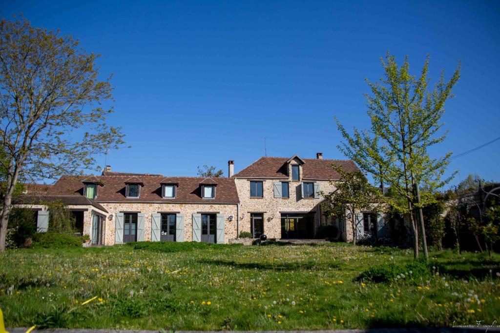 ein großes Backsteinhaus mit einem Rasenplatz in der Unterkunft La ferme Du Vieux Moulin in Saint-Germain-lès-Arpajon