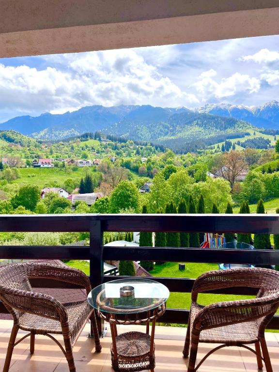 a balcony with two chairs and a glass table at Almir Bran in Bran