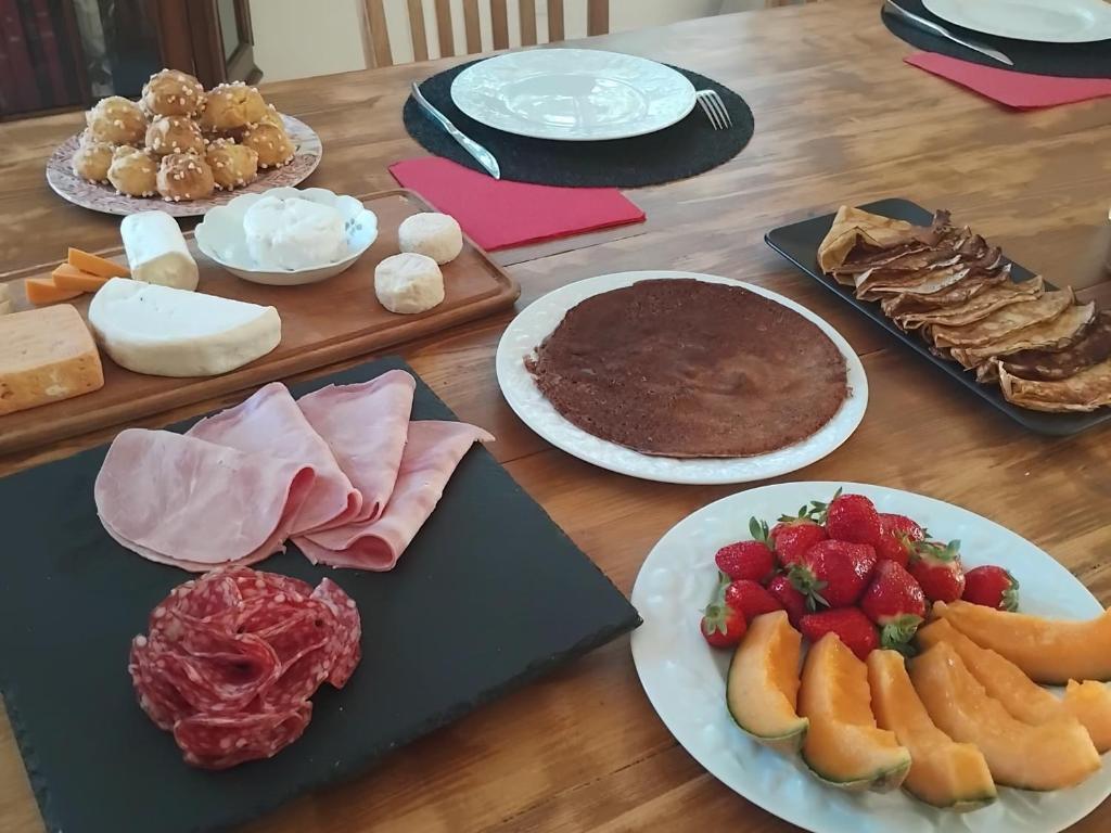 une table en bois avec des assiettes de nourriture et des desserts dans l'établissement l'aedes, à Orange