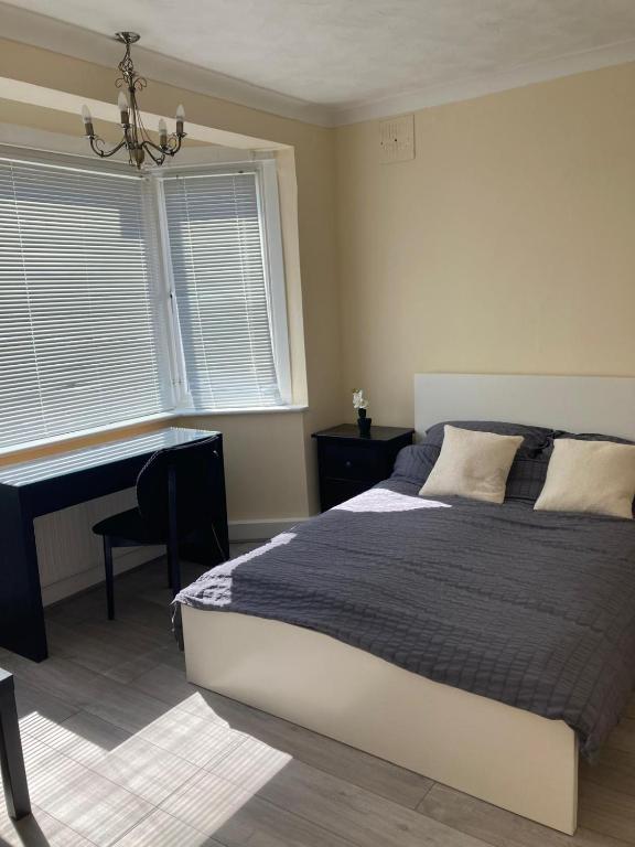 a bedroom with a bed and a desk and a window at Arundel Road, RM30RX in Harold Wood