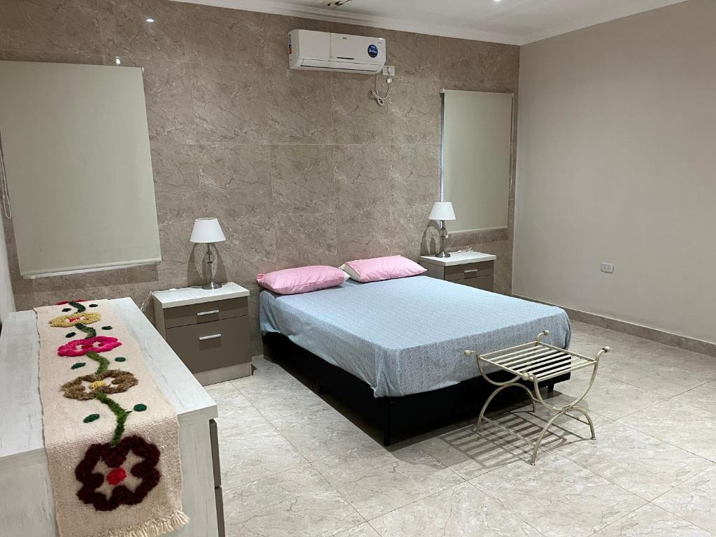 ein Schlafzimmer mit einem Bett, zwei Tischen und einem Stuhl in der Unterkunft Casa en Yanda, sobre Ruta Nacional 9, salida directa Autódromo in Zanjón