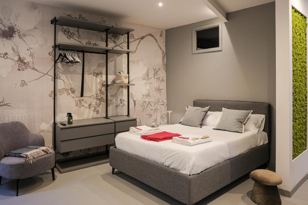 a bedroom with a large bed and a chair at Moss & Stone - 3 min walk to piazza Vittoria in Brescia