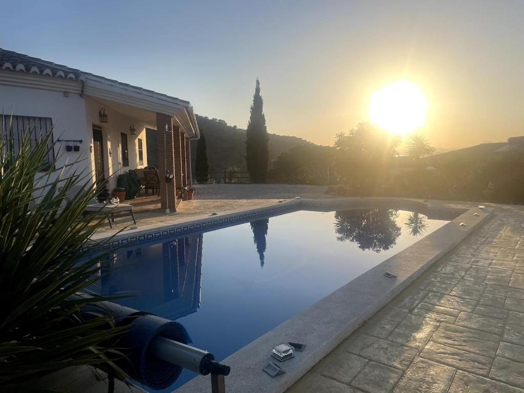 a swimming pool with the sun setting behind a house at Luxury Pool Villa in Arenas - Andalusia in Los Valverde