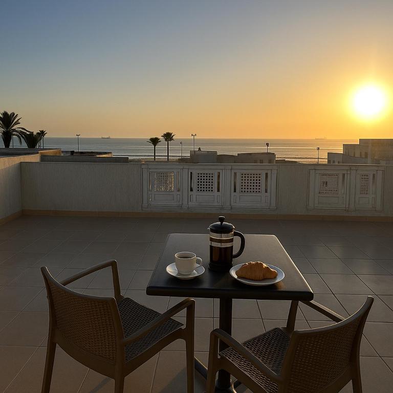 a table with a cup of coffee and two chairs at Sea View Private Terrace - Fibre Wi-Fi & Netflix in Essaouira