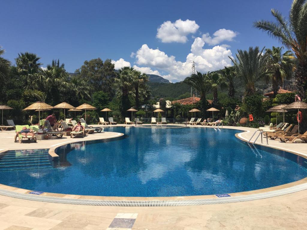 a large pool with chairs and umbrellas at a resort at Asur Hotel & Aparts & Villas in Dalyan