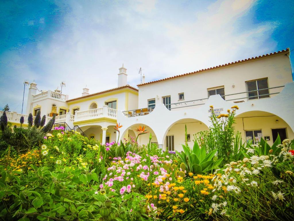 una gran casa blanca con flores en el patio en Residencia Quinta do Poço Guesthouse, en Sagres