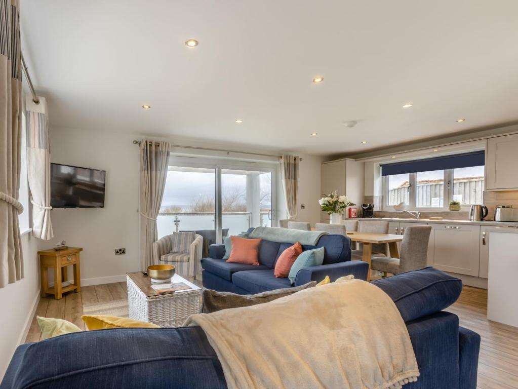 a living room with a blue couch and a kitchen at 3 Bed in Westward Ho 65536 in Westward Ho