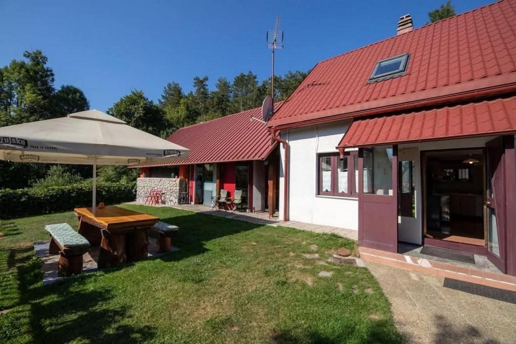 a house with a picnic table and an umbrella at Family-friendly apartments with swimming pool Lic, Gorski kotar - 23685 in Fužine