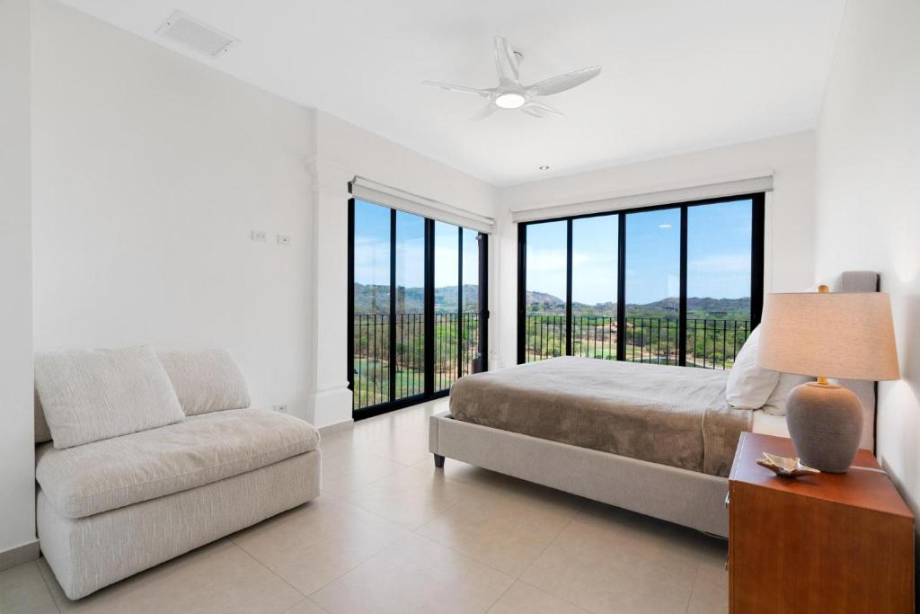 Un dormitorio con una cama y un sofá y ventanas. en Bougainvillea 4315 Ph- Luxury 3 Bedroom Ocean View Resort Condo, en Brasilito