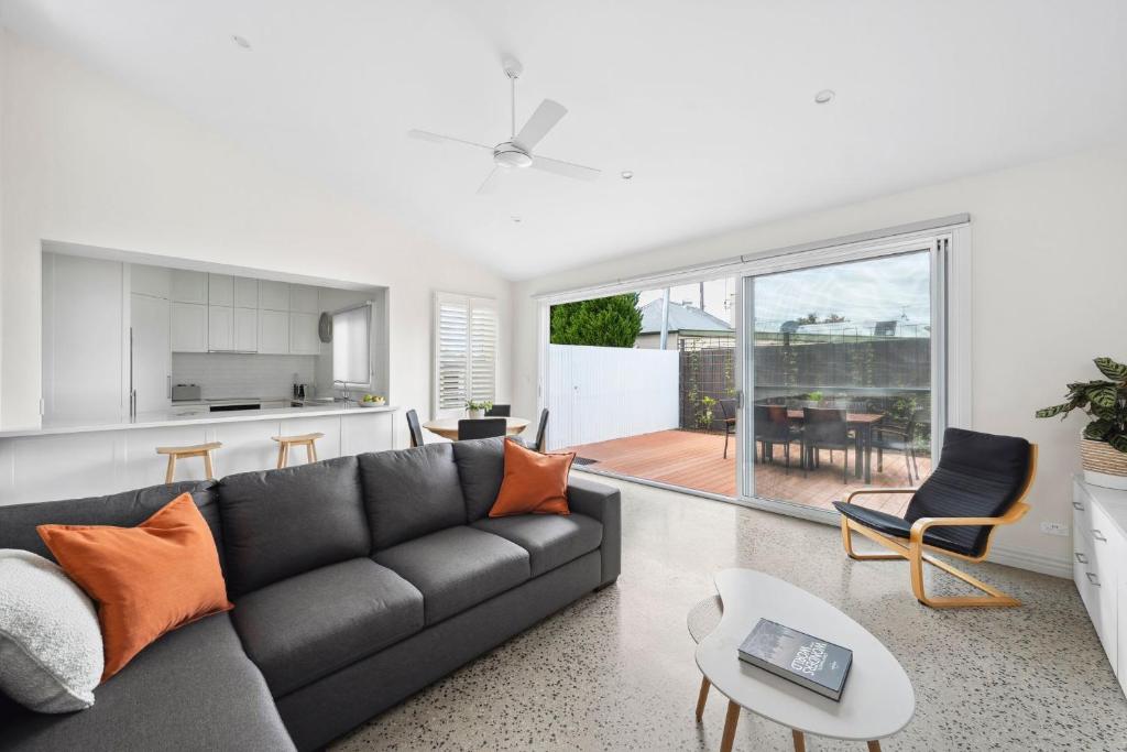 Una sala de estar con un sofá negro y una cocina. en Geelong West Gem, en Geelong West