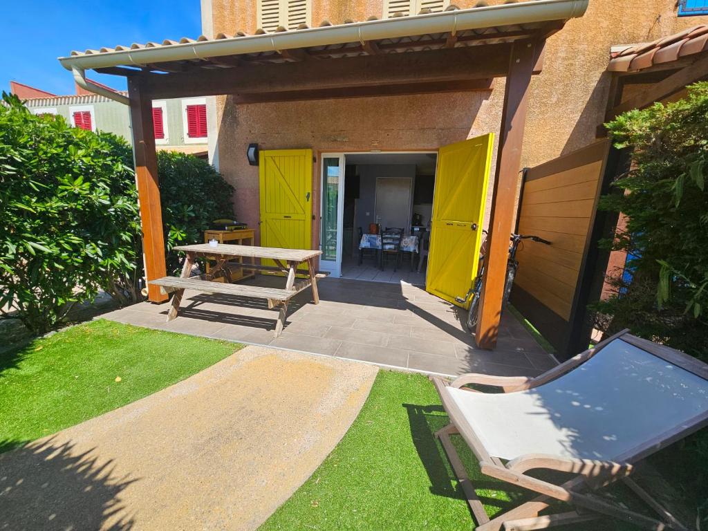 un patio avec une table de pique-nique et un banc dans l'établissement Charmante maisonnette - Piscine, sauna, jacuzzi, au Barcarès