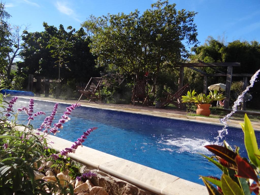 a swimming pool with a fountain in a yard at Pousada Canto da Lua in São Bento do Sapucaí